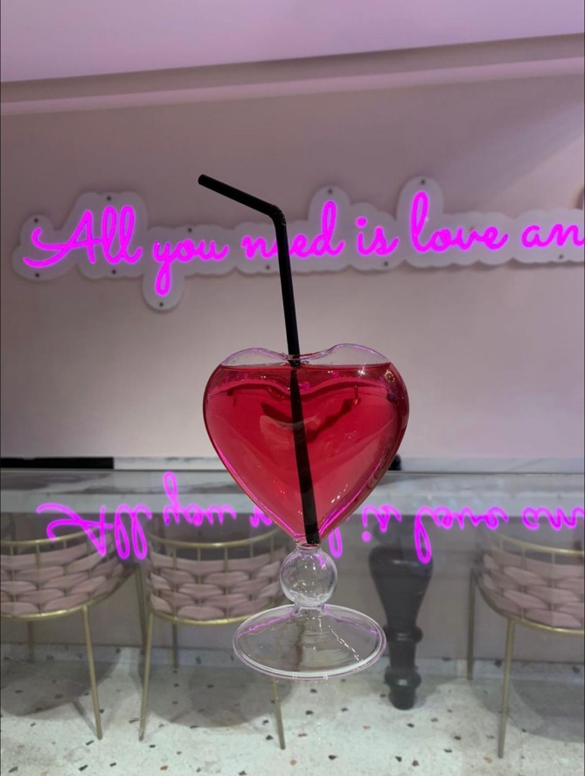 Cocktail cœur rose devant le néon All you need is love and tea